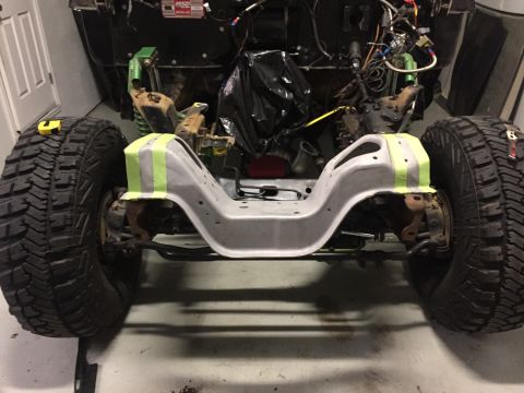 1979 Ford Bronco - The front suspension and chassis of a vehicle are shown, with large off-road tires mounted. The chassis is painted gray and has bright gree…