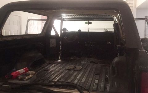 1979 Ford Bronco - The interior of a classic Ford Bronco is shown from the rear, looking forward towards the dashboard and steering wheel. The rear cargo area…