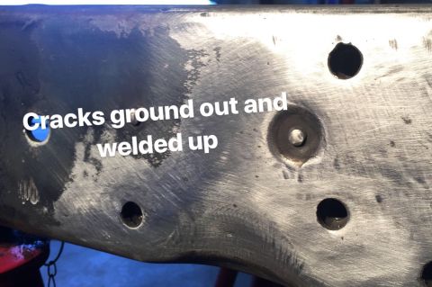 1979 Ford Bronco - A close-up view of a metal vehicle frame section showing ground-out cracks that have been welded up. Several holes are visible in the frame…