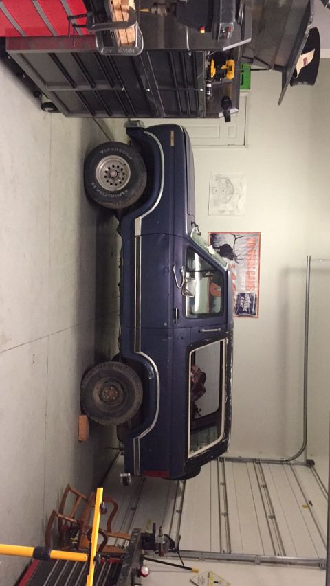 1979 Ford Bronco - A dark blue Ford Bronco is parked inside a garage next to a large toolbox. The garage door is open, revealing a white ribbed door.