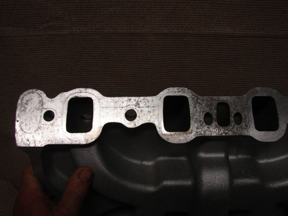 Cast iron intake manifold with gasket surface showing ports and wear.
