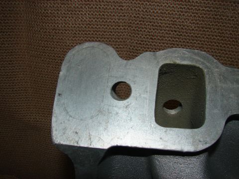 1973 Ford Ranchero - Close-up view of a cast metal intake manifold with two ports. One port is rectangular and the other is circular, with a smaller circular ho…