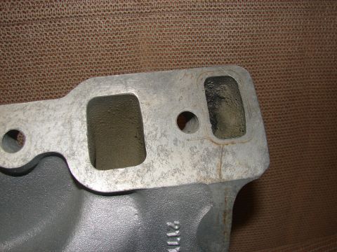 1973 Ford Ranchero - A close-up view of a gray engine intake manifold with two rectangular ports. The metal surface shows signs of wear and some discoloration.