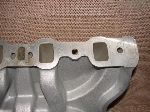 1973 Ford Ranchero - A close-up, angled view of a silver aluminum intake manifold with four ports visible. The manifold is resting on a textured brown surface.