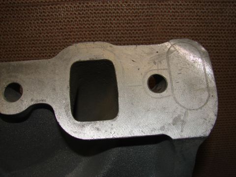 1973 Ford Ranchero - A close-up, angled shot shows the top of a dark gray engine part, likely an intake manifold, with a silver metal flange. The flange has a r…