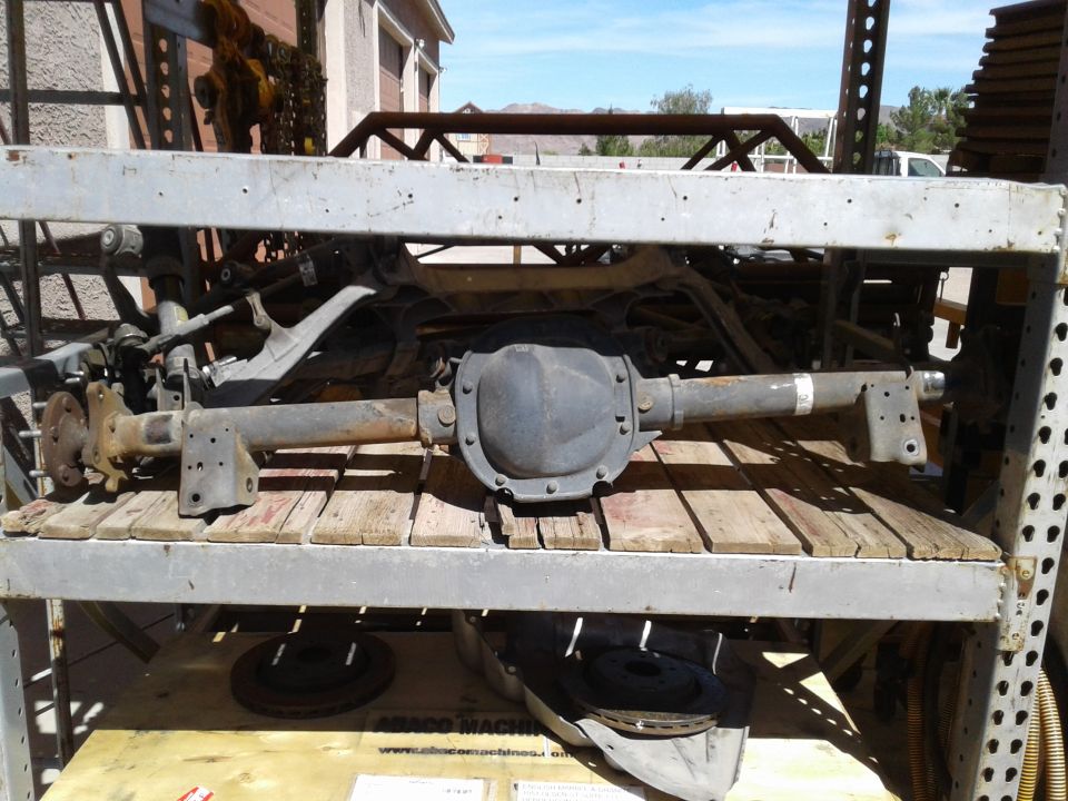 Heavy-duty rear axle assembly on a metal rack with wooden planks.