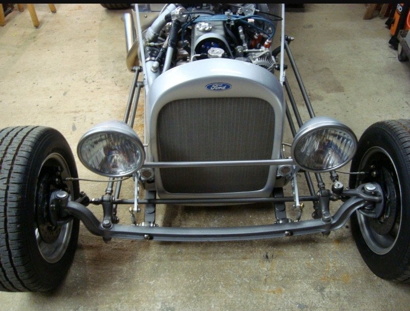 Front view of a custom hot rod with a silver Ford grille and two round headlights.