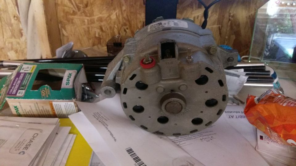 Gray alternator part on papers and box of screws.