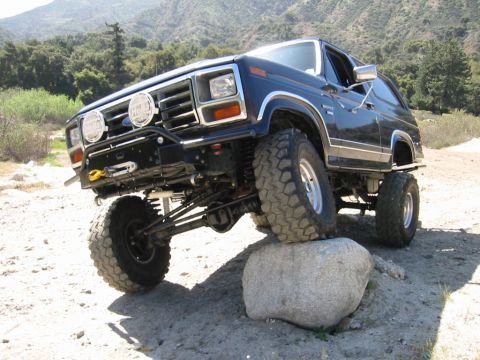 1985 Ford Bronco - This modified Ford Bronco is shown off-roading over a large rock.