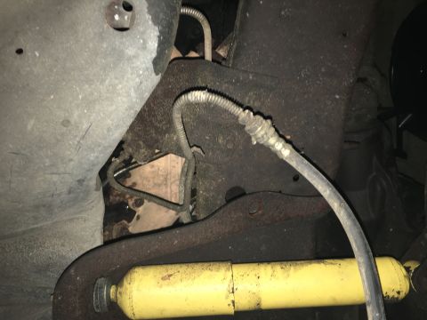 1980 Ford Bronco - This is an underside view of a vehicle, showing a yellow shock absorber and brake lines attached to the frame. The components appear to be…