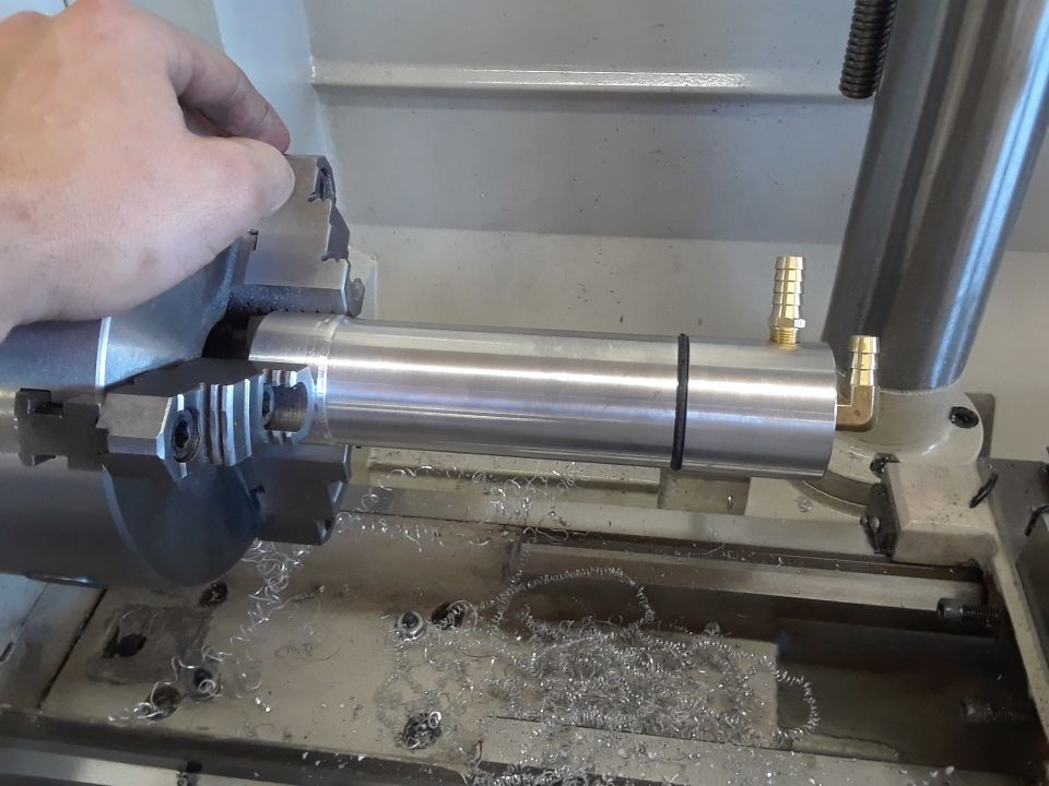 Hand adjusting metal part in lathe chuck with metal shavings.