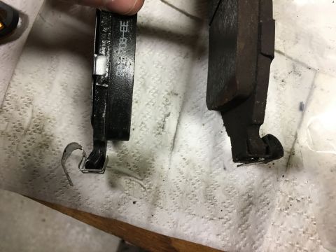 1980 Ford Bronco - Two brake pads are shown, one black and one rusty brown, lying on a white paper towel. The black brake pad has white text that reads 'BB-Y0…
