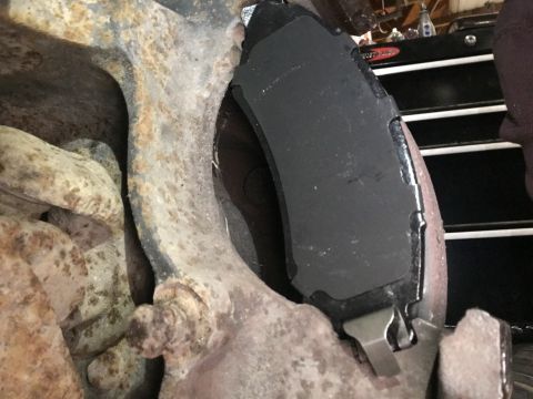 1980 Ford Bronco - A close-up view shows a new brake pad installed on a rusty suspension component, likely from a 1980 Ford Bronco.