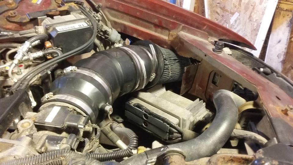 Engine bay with custom intake system, air filter, and electronic module.