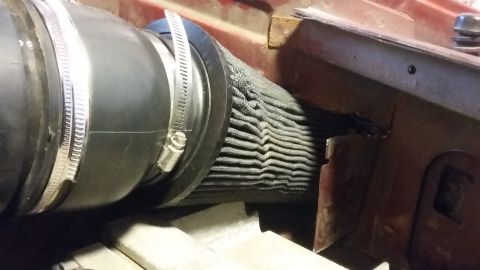 2000 Pontiac Grand Prix - A close-up view shows a black air intake hose connected to a pleated gray air filter. The filter is secured with a metal clamp and is posit…