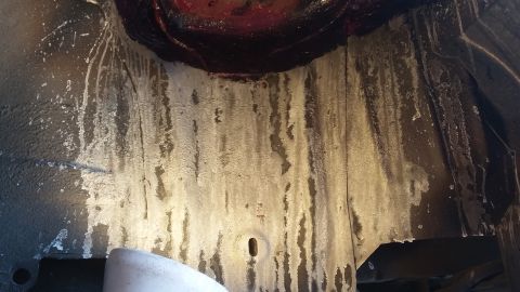 2000 Pontiac Grand Prix - This is a close-up, low-angle shot of the undercarriage of a vehicle, likely a 2000 Pontiac Grand Prix, showing significant white residue o…