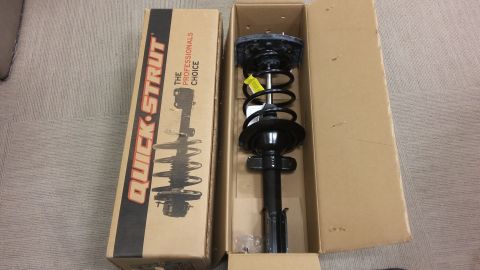 2000 Pontiac Grand Prix - A new Quick-Strut assembly is shown in its cardboard packaging, next to an open box revealing the strut and coil spring unit.