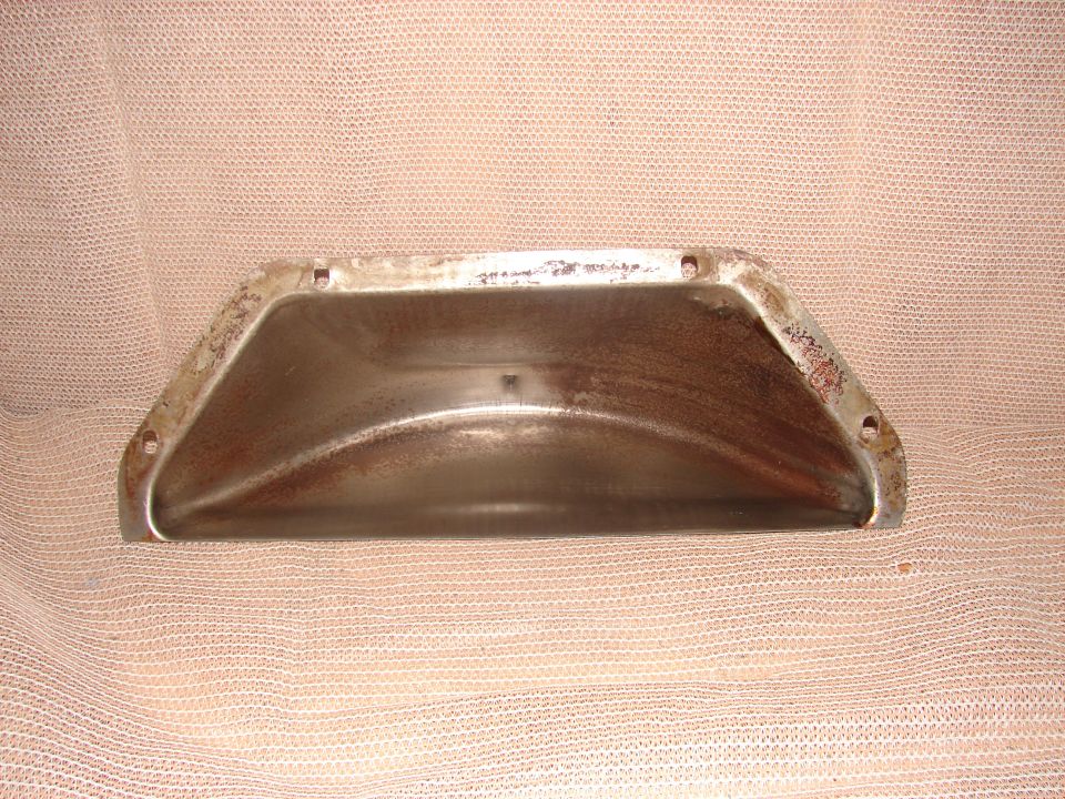 Rusted metal oil pan with mounting holes on textured fabric.