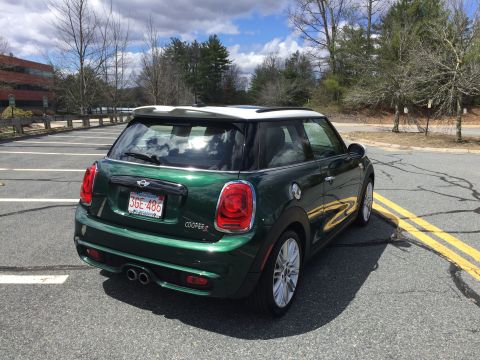 2001 Ford Crown Victoria - The rear driver side quarter of a dark green Mini Cooper S is shown parked in an empty asphalt lot with yellow painted lines. The car has a…