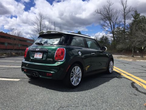 2001 Ford Crown Victoria - The rear passenger side of a dark green Mini Cooper S is parked on an asphalt lot with yellow double lines. The car has a white roof and sp…