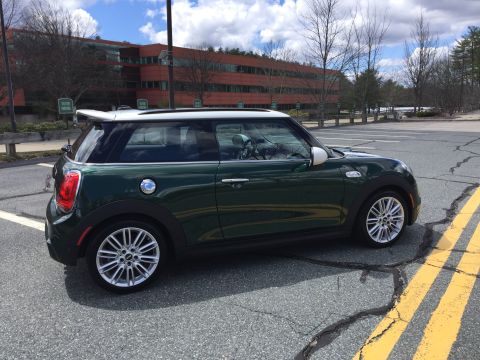 2001 Ford Crown Victoria - A dark green Mini Cooper with a white roof is parked in an asphalt parking lot with yellow lines. A modern office building is visible in th…
