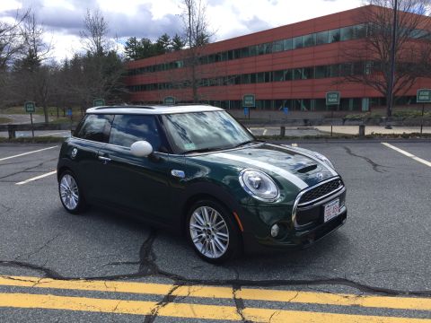 2001 Ford Crown Victoria - A dark green Mini Cooper S with white racing stripes is parked in an asphalt parking lot in front of a modern orange office building. The c…