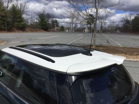 2001 Ford Crown Victoria - The rear top portion of a dark colored vehicle with a white roof and a sunroof is shown. A black antenna and a white spoiler are visible on…