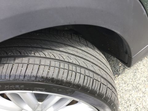 2001 Ford Crown Victoria - A close-up, low-angle shot of the tread and sidewall of a black tire, mounted on a silver alloy wheel. The tire is positioned under the whe…