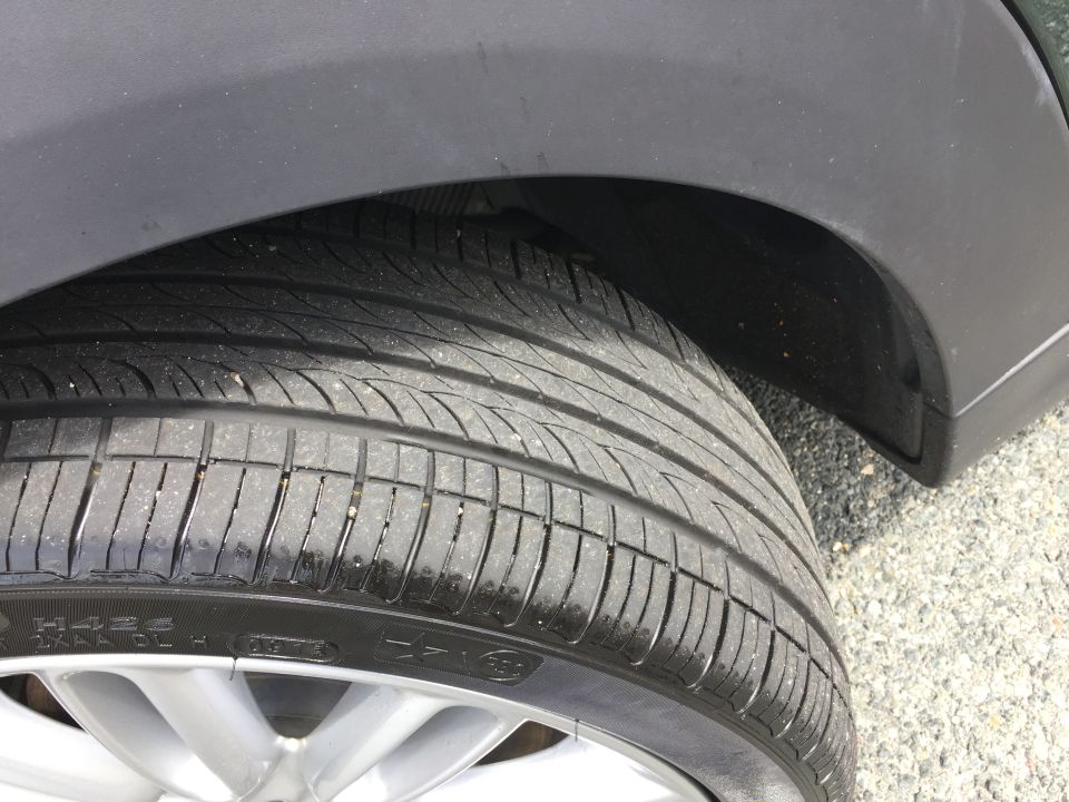 Close-up of a black tire and silver alloy wheel under a vehicle's wheel well.