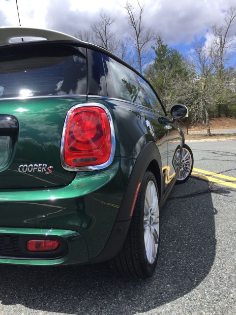 2001 Ford Crown Victoria - The rear driver's side of a dark green Mini Cooper S is shown parked on an asphalt road with yellow lane markings. The car features chrome…