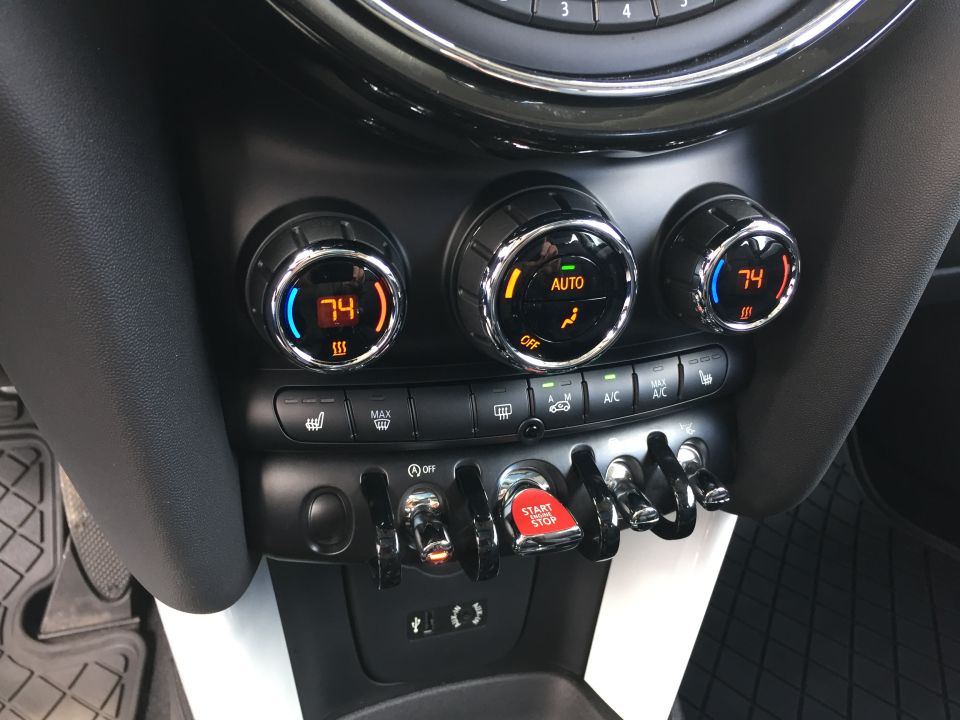 Close-up of a car's center console with climate controls and a start/stop button.