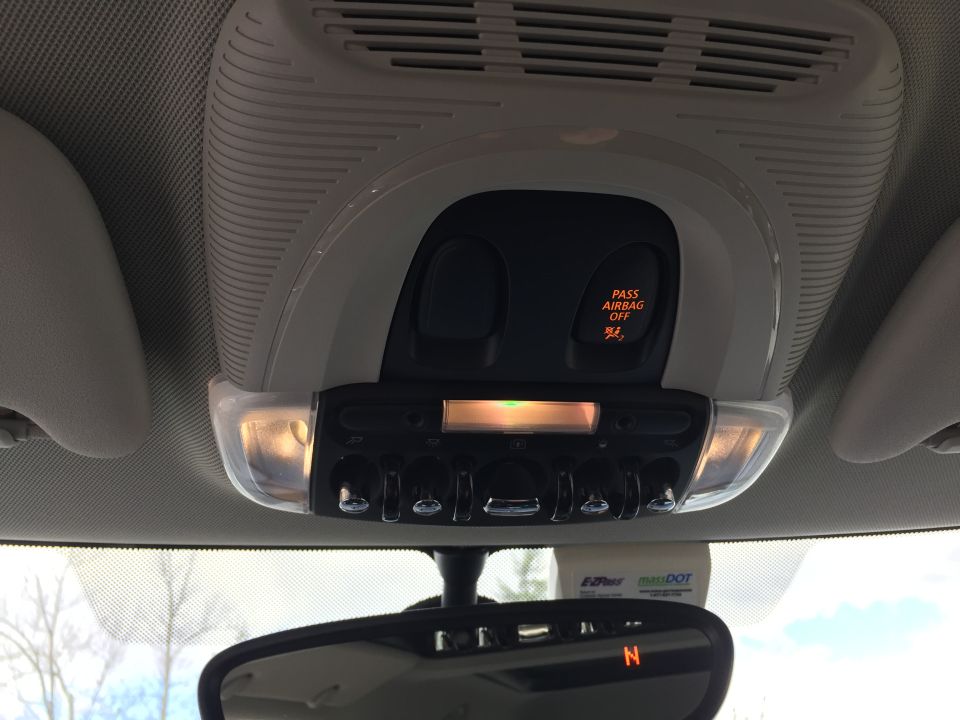Car overhead console with airbag light, buttons, and E-ZPass transponder on windshield.
