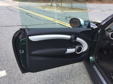 2001 Ford Crown Victoria - The open driver's side door of a dark green Mini Cooper, showing the interior door panel with a white accent trim and black armrest. The ex…