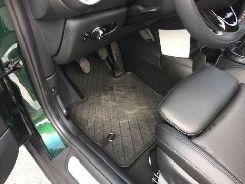 2001 Ford Crown Victoria - The interior driver's side footwell of a green vehicle shows a black diamond-patterned floor mat with a metal clip. The pedals, door sill,…