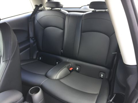 2001 Ford Crown Victoria - The interior of a car shows black leather rear seats with visible ISOFIX anchors and seat belts. A cup holder is visible in the foreground.