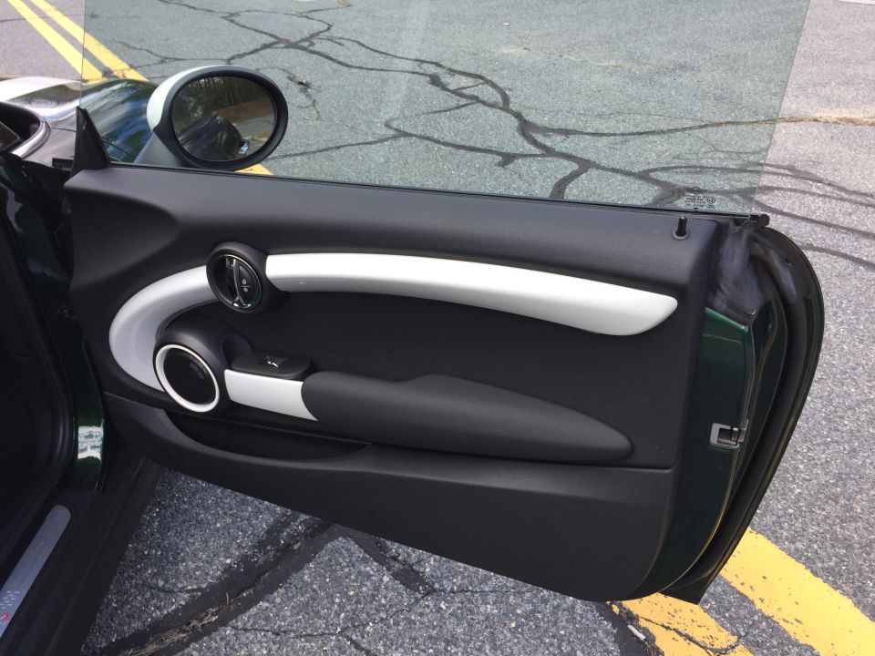 Interior of a dark green Mini Cooper door panel with silver and black accents.