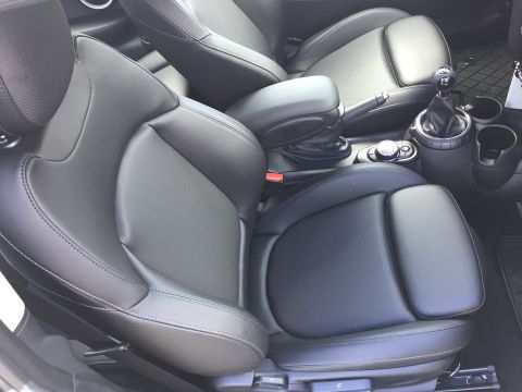 2001 Ford Crown Victoria - The interior of a modern car shows black leather front seats, a center console with a gear shifter and cup holders, and an armrest.