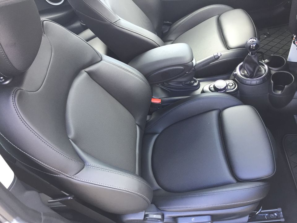 Black leather car interior with front seats, gear shifter, and center console.