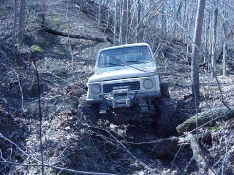 1992 Ford Bronco - This Suzuki Samurai is navigating a challenging, off-road trail through a dense forest.