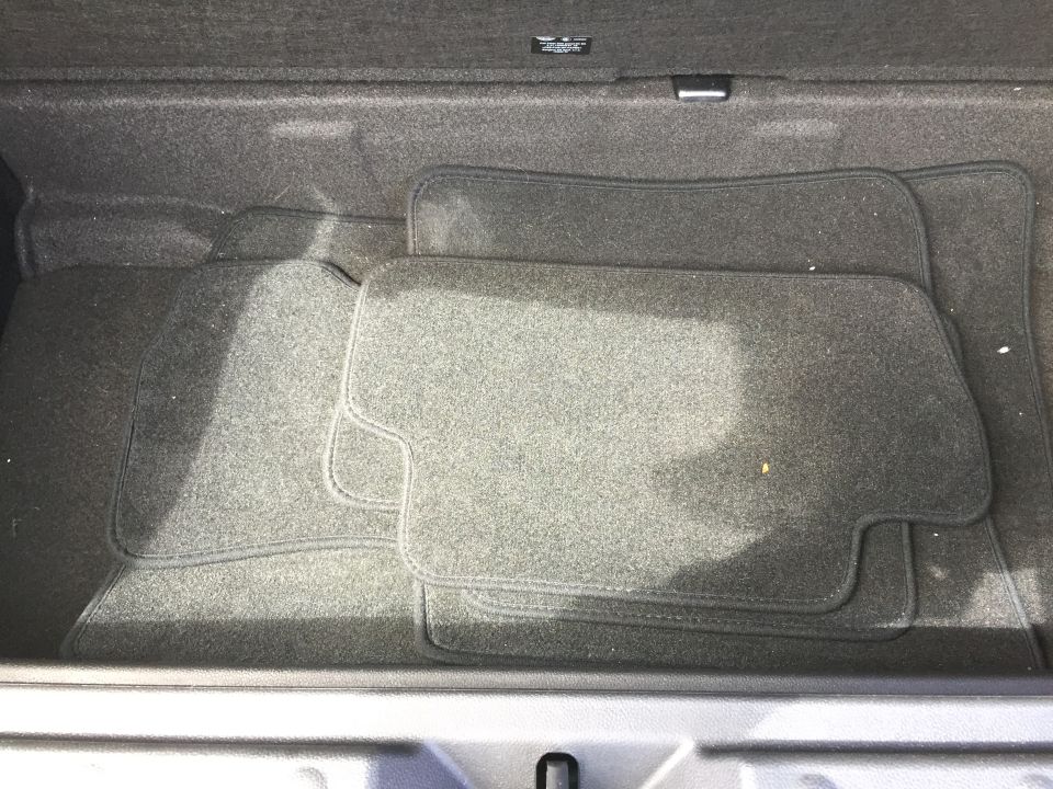 Car trunk interior with dark gray carpet floor mats.