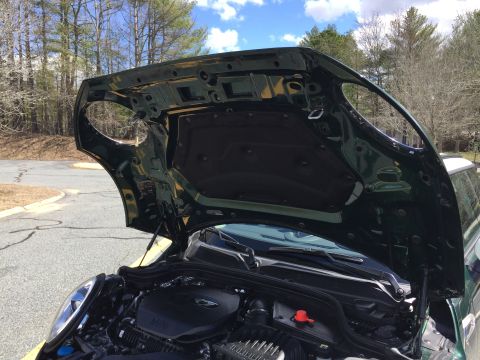 2001 Ford Crown Victoria - The open hood of a dark green Mini Cooper reveals the engine bay and the underside of the hood with its sound deadening material. The vehic…
