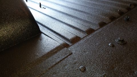 1968 Ford Bronco - A close-up, angled view of a dark, textured surface, likely the bed of a truck or similar vehicle, with distinct ridges and some visible fa…