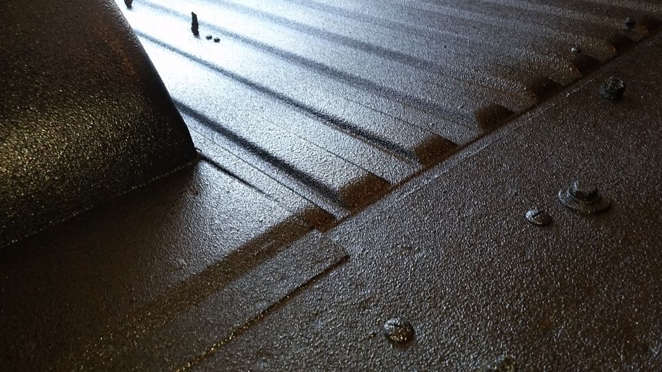 Close-up of a dark, textured, ridged surface with fasteners, possibly a truck bed.
