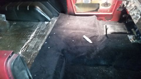 1968 Ford Bronco - The interior of a vehicle is shown with black carpet being laid over a clear plastic vapor barrier. A white object, possibly a tool or mark…