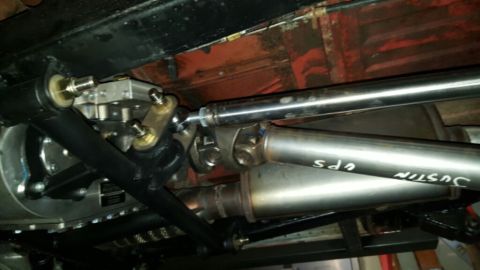 1968 Ford Bronco - Underside view of a vehicle's drivetrain, showing a driveshaft connected to a differential with a U-joint. A portion of the exhaust system…