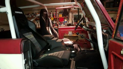 1968 Ford Bronco - The interior of a red and white vehicle, likely a Ford Bronco, is shown with a white roll cage and two Bride racing seats. The vehicle is p…