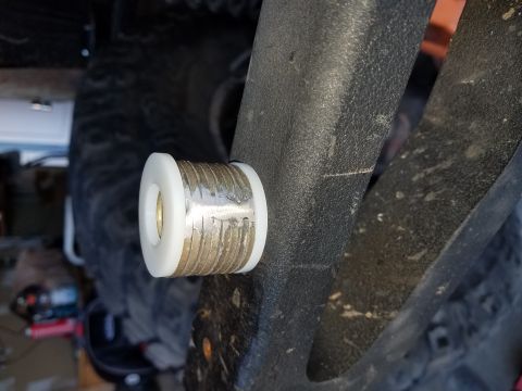 1968 Ford Bronco - A close-up view of a white and metallic bushing installed on a black, textured component of a vehicle. The bushing appears to be a suspensi…