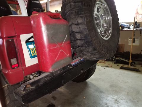 1968 Ford Bronco - The rear driver's side of a red vehicle is shown, featuring a mounted red jerry can and a spare tire with a chrome rim. A license plate wit…