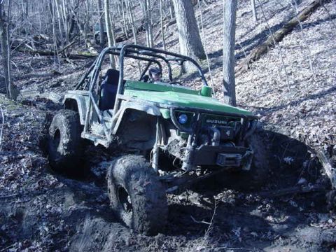 1992 Ford Bronco - An off-road vehicle tackles a challenging muddy trail in a dense forest environment.