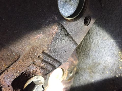 1996 Ford Bronco - A close-up view of heavily rusted metal components, likely from the undercarriage of a vehicle. Visible are bolt heads, mounting brackets,…